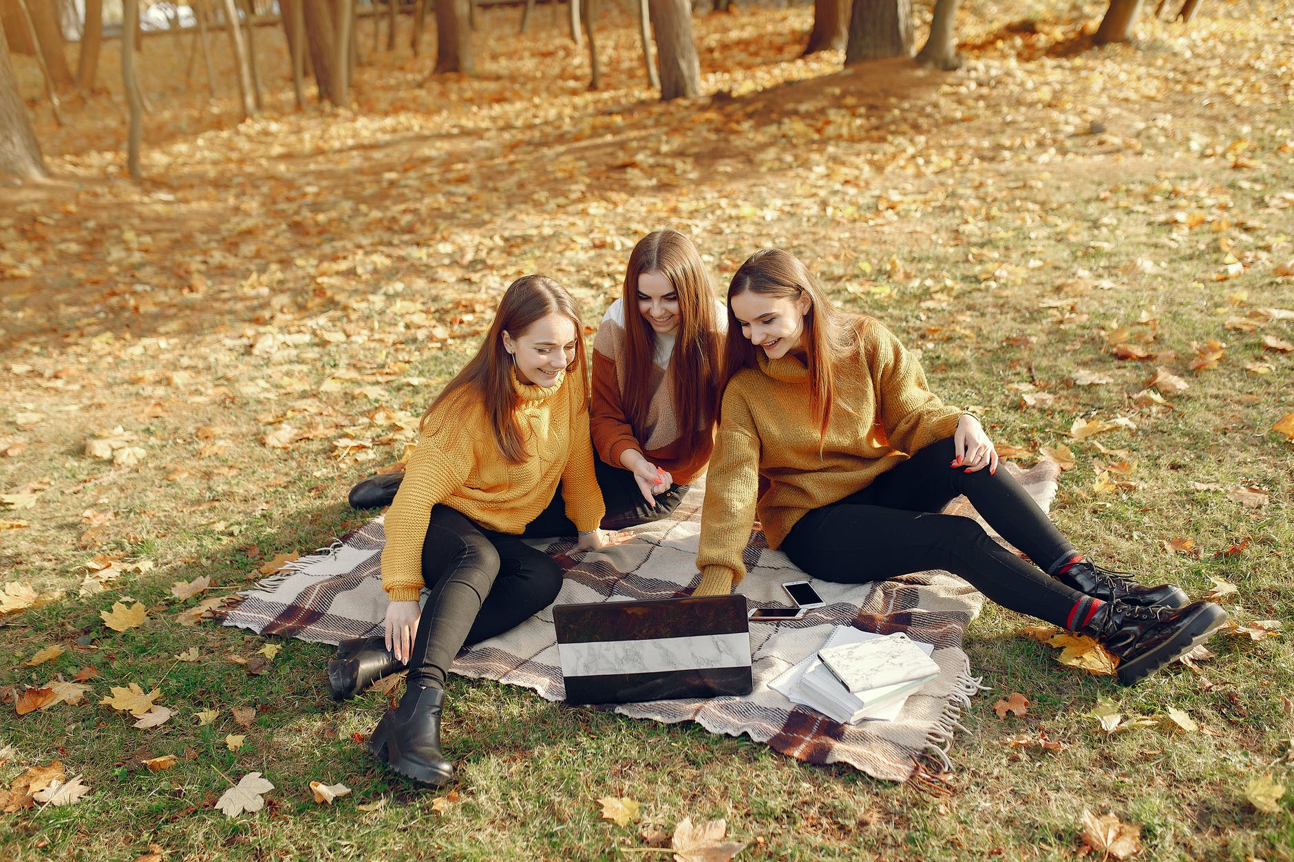 happy students using laptop in autumn park